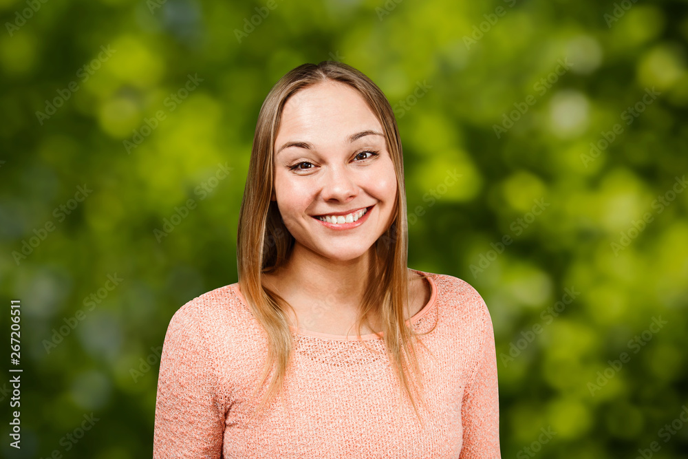 Close up portrait of beautiful smiling young woman in a beige shirt, on green bokeh background Close up portrait of beautiful smiling young woman in a beige shirt, on green bokeh background