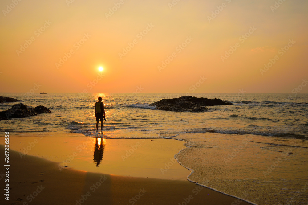 Silhouette of a man watching sunset over Anjuna beach in Goa.