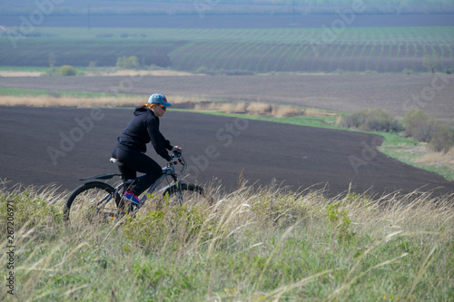 A woman on a bike rides over rough terrain.