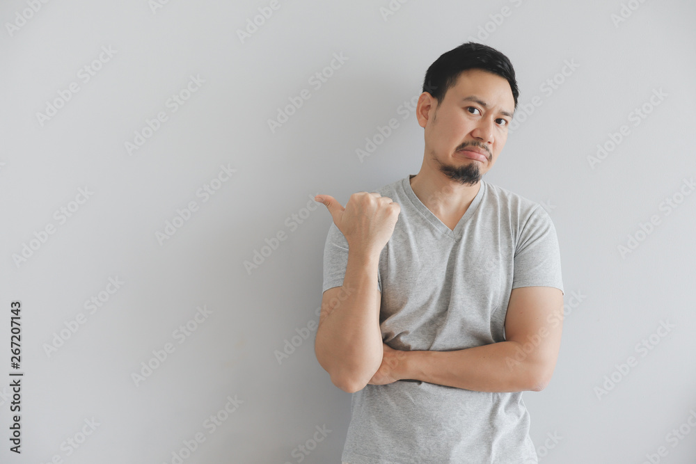 Hate face of man in grey t-shirt with hand point on empty space. Hate face of man in grey t-shirt with hand point on empty space.