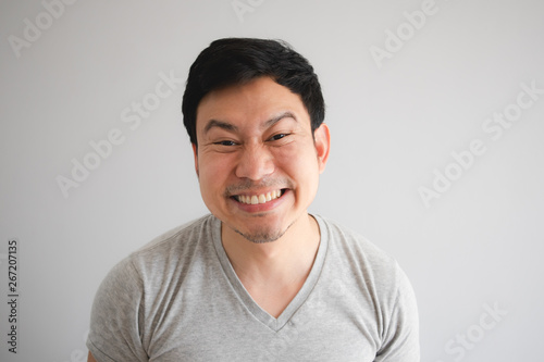 Very happy funny face of man with a big innocent smile in grey t-shirt