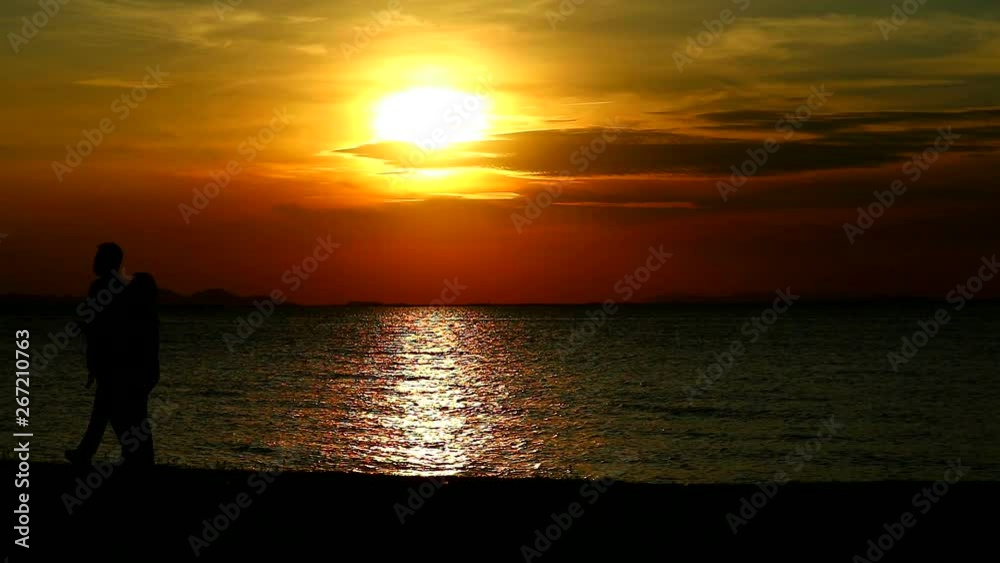 Couple lover walking on beach while sunset on the sea Couple lover walking on beach while sunset on the sea