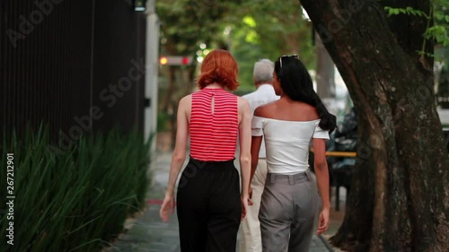 Two female friends walking toether in the sidewalk street photo