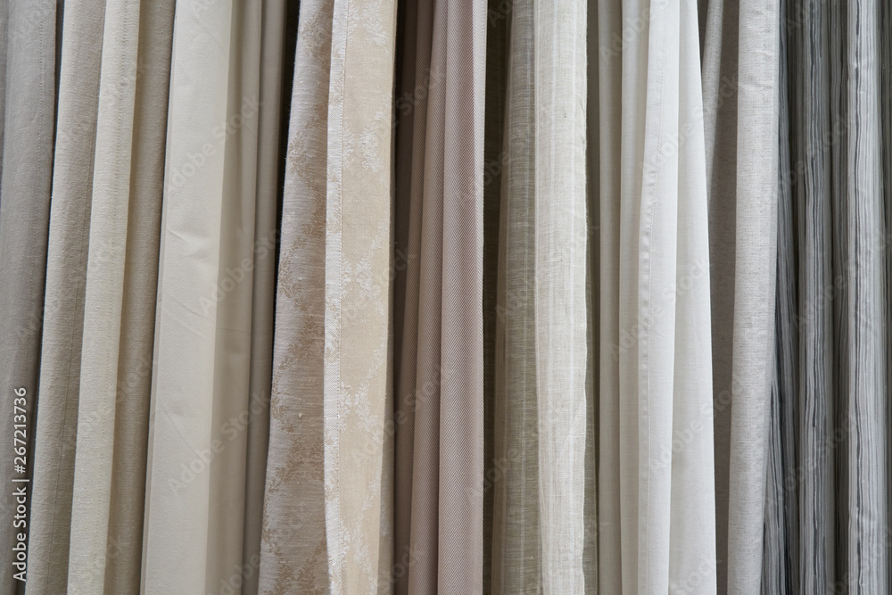 Fototapeta premium Beautiful curtains of different colors hang on the stand for sale. Curtains hang on the stand in the store