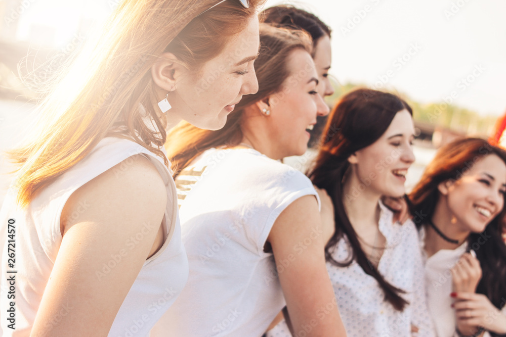 Group of young happy girls friends enjoy life on summer city street, sunset background Group of young happy girls friends enjoy life on summer city street, sunset background