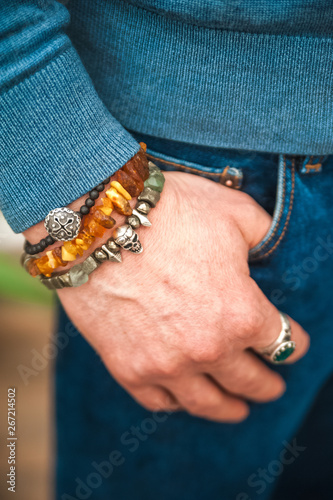 Male hand in a bracelet with a skull in the pocket of jeans close up and copy space