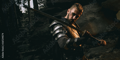 mystery scarface knight in armor with sword and crossbow in the forest