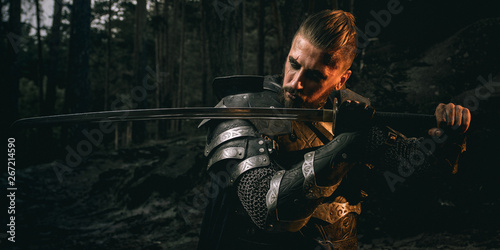 mystery scarface knight in armor with sword and crossbow in the forest