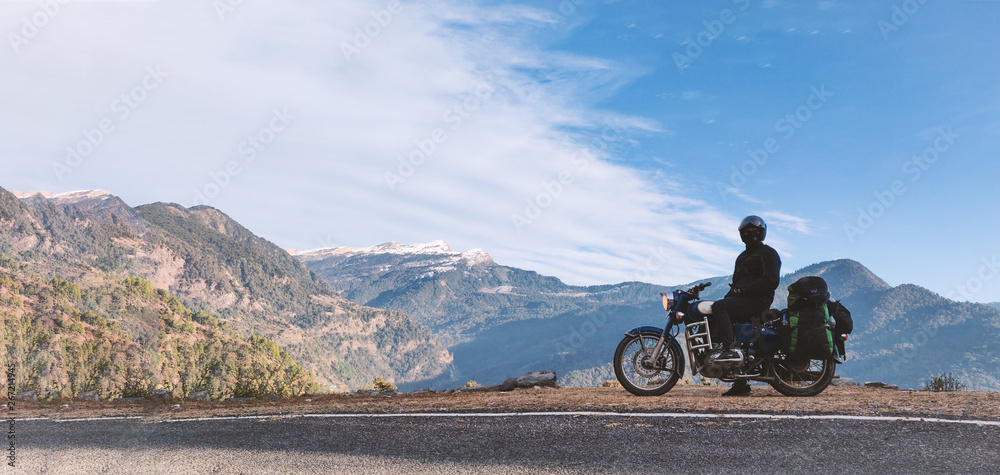 A young unidentifiable man sitting on his motorbike with view of Himalayan mountains. A young unidentifiable man sitting on his motorbike with view of Himalayan mountains.