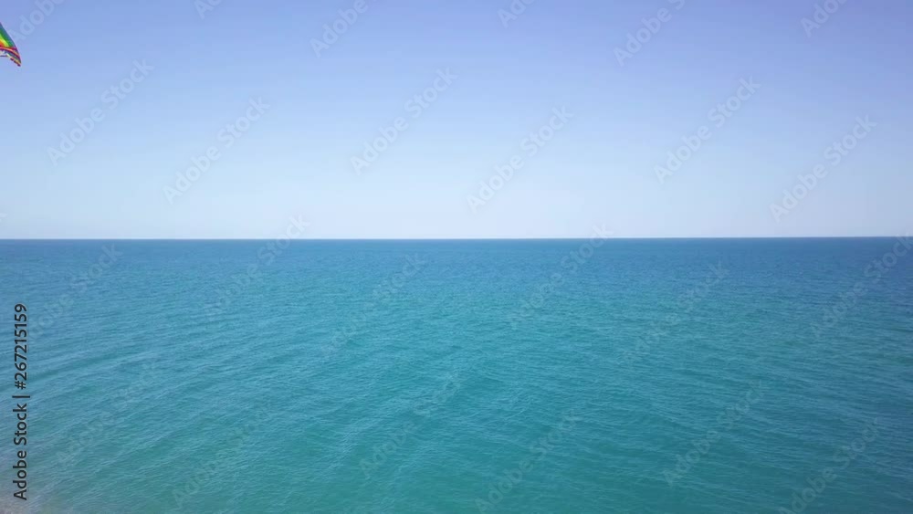 Aquilone colorato che vola in spiaggia con sfondo del mare blu. Aquilone colorato che vola in spiaggia con sfondo del mare blu.