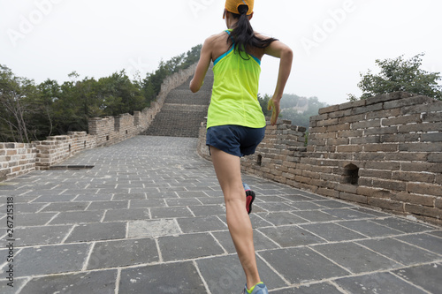 young woman trail runner running at great wall on the top of mountain photo