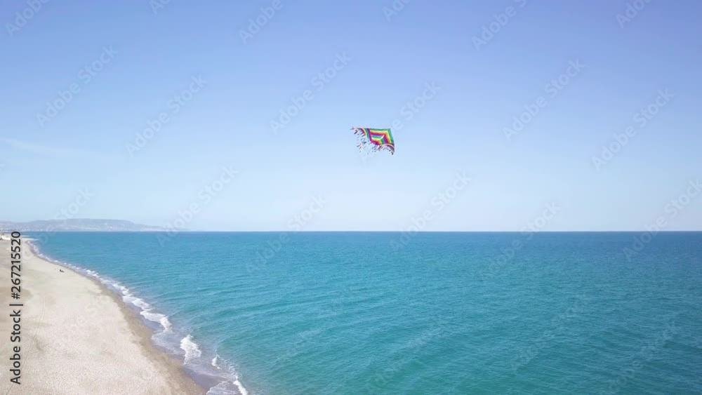 Aquilone colorato che vola in spiaggia con sfondo del mare blu. Aquilone colorato che vola in spiaggia con sfondo del mare blu.