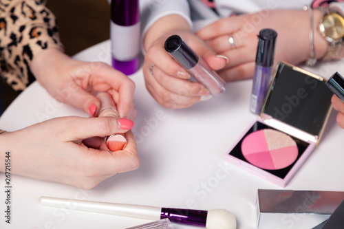 Closeup collection testers of professional cosmetic in makeup artist hands on white background. Make up brush, lip gloss, lipstick, pink blusher. Concept visagiste, stylist, preparing for wedding