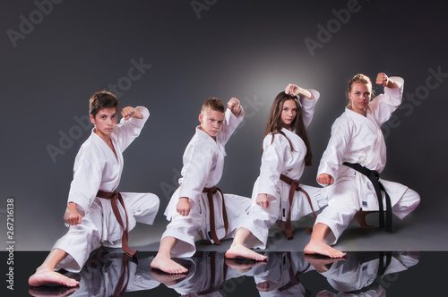 Group of young karate players doing kata on the gray background photo