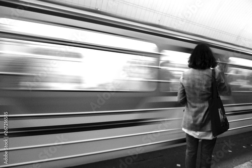 Young lady waiting for the train in black and white. Young attractive girl on a platform.