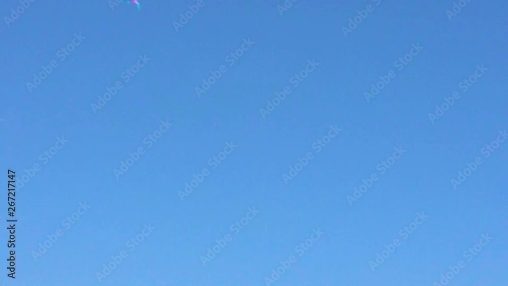 Aquilone colorato che vola nel cielo blu con il vento. Ripresa sulla spiaggia vicino al mare. Aquilone colorato che vola nel cielo blu con il vento. Ripresa sulla spiaggia vicino al mare.