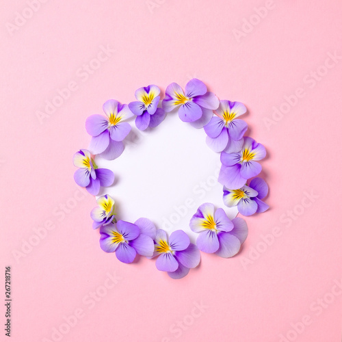 Creative flat lay composition: circle blank paper and blooming flower petals on pink background. Top view, floral round frame, abstract design. Invitation, greeting card or an element for your design