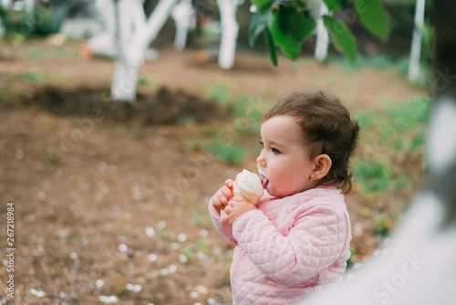 little girl in the garden on the background of greenery and trees very cute eating ice cream in a waffle Cup