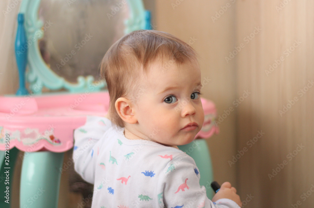 a small child plays in front of a toy mirror in the nursery a small child plays in front of a toy mirror in the nursery