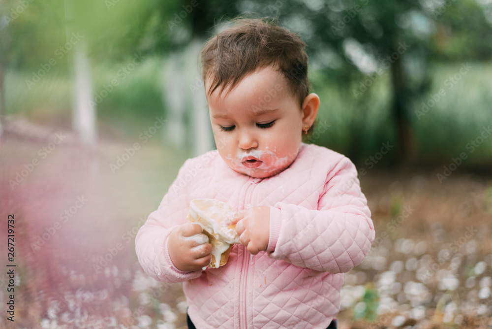 little girl in the garden on the background of greenery and trees very cute eating ice cream finger in a waffle Cup little girl in the garden on the background of greenery and trees very cute eating ice cream finger in a waffle Cup