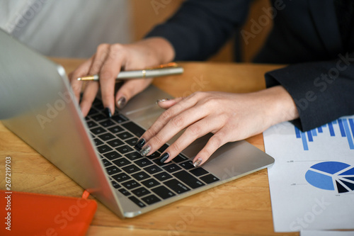 Female executives are using laptop computer in office.