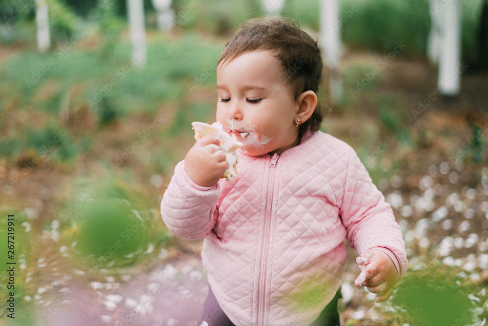 little girl in the garden on the background of greenery and trees very cute eating ice cream in a waffle Cup little girl in the garden on the background of greenery and trees very cute eating ice cream in a waffle Cup