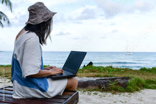 Fototapeta Naklejka Na Ścianę i Meble -  Female travelers are using laptop computer on the beach.