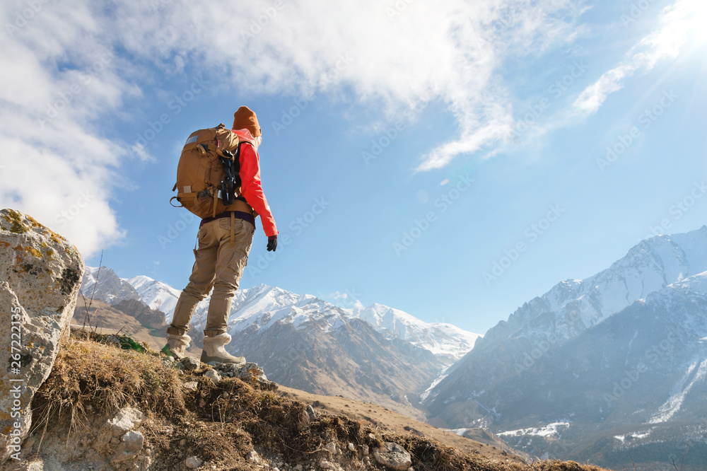 Portrait of photographer hipster tourist girl in sunglasses and a hat against the background of snow-covered Caucasus mountains. Photo travel concept