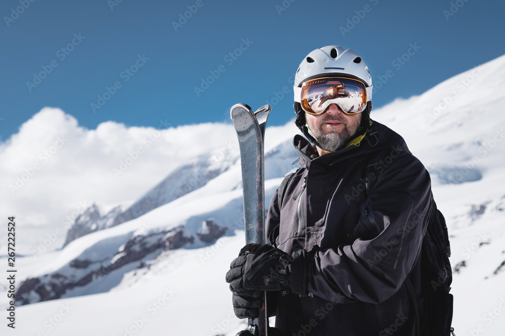 Portrait athlete skier in helmet and ski mask against the snow-capped  mountains of a ski resort with a reflection of the Caucasian mountains in  the mask Stock Photo | Adobe Stock