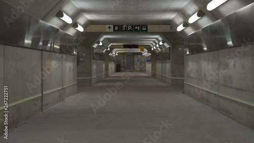 Empty concrete pedestrian tunnel under a train station. An empty concrete subterranean pedestrian tunnel lines with lights and reflective metal It is under a GO train station in Canada photo