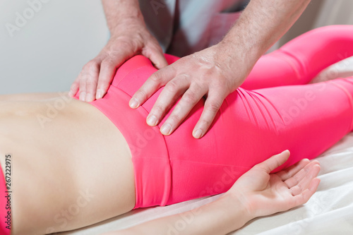 Close-up of a young girl's spine base editing by a male physiotherapist of visceral massage. The hands of the doctor set and knead the tailbone of the patient