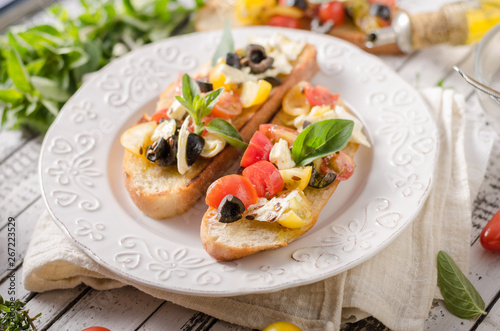 Crostini with tomatoes and olives on beautiful plate