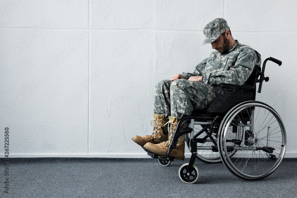 Depressed disabled military man in uniform sitting in wheelchair with bowed head - obrazy, fototapety, plakaty 