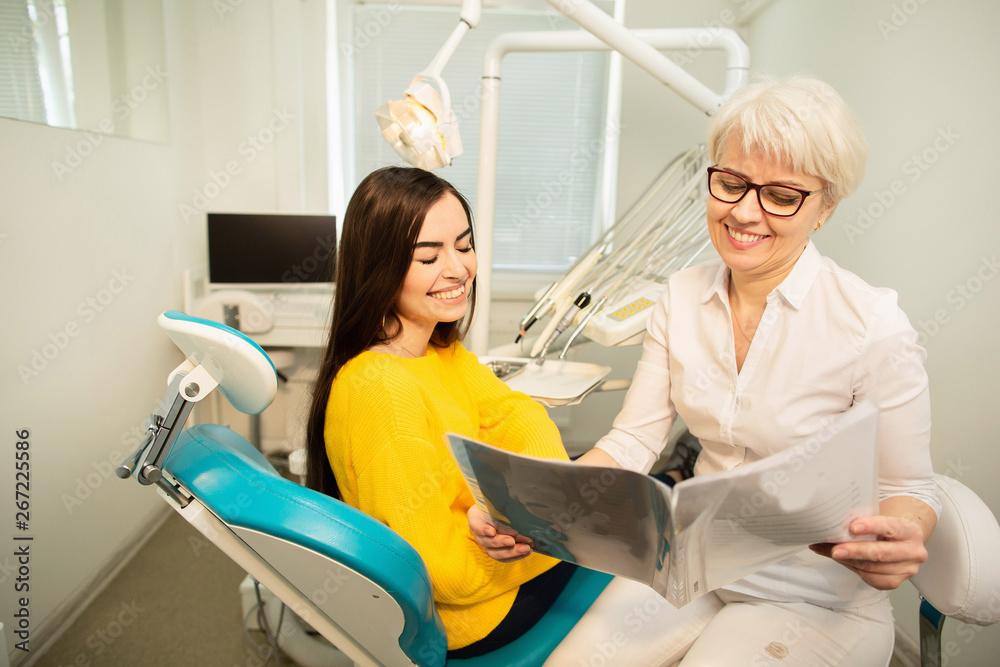 Obraz premium Professional doctor shows to the patient picture of healthy teeth in his medical dental office. Secret of healthy teeth