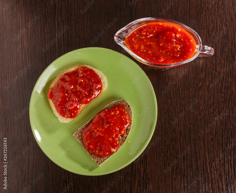 Pieces of rye bread and thick tomato sauce on a plate on the table. Pieces of rye bread and thick tomato sauce on a plate on the table.