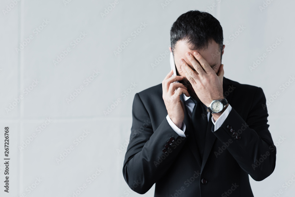 disappointed man in black suit using smartphone and holding hand on face disappointed man in black suit using smartphone and holding hand on face