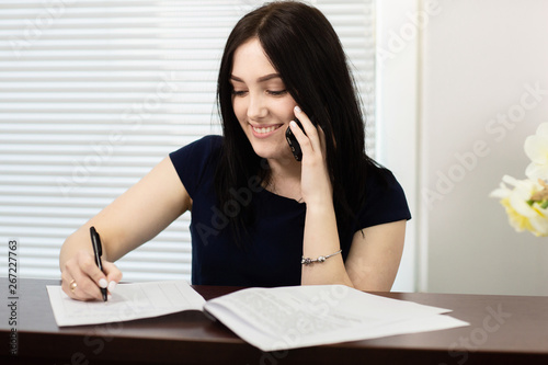 Beautiful girl at the reception desk answering the call in dental office