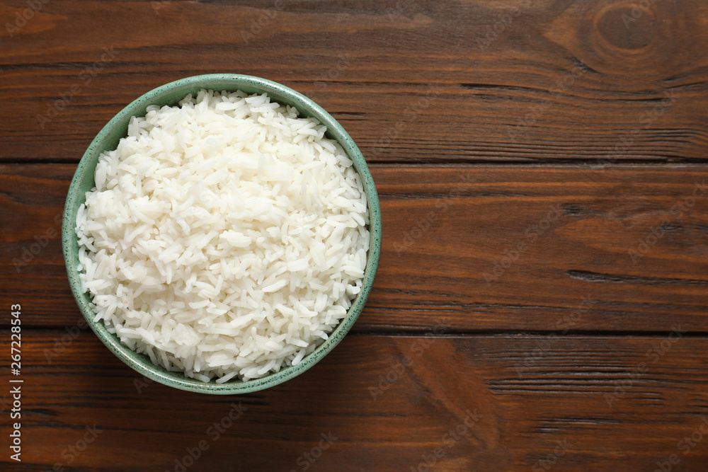 Bowl of tasty cooked rice on wooden background, top view. Space for text Bowl of tasty cooked rice on wooden background, top view. Space for text