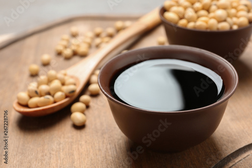 Bowl of soy sauce and beans on wooden board, closeup