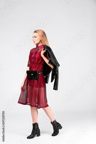 Young stylish woman in trendy shoes with bum bag on light background