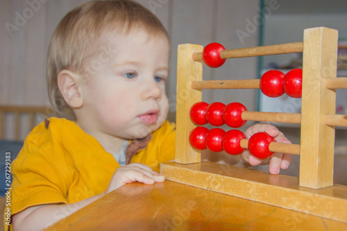 A child plays with a toy clock. The boy studies time, hours. A child learns to count.