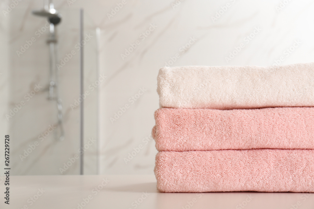 Stack of clean towels on table in bathroom, closeup. Space for text Stack of clean towels on table in bathroom, closeup. Space for text