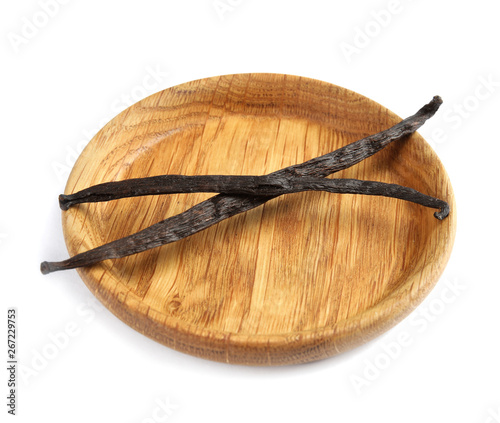Wooden plate with aromatic vanilla sticks on white background