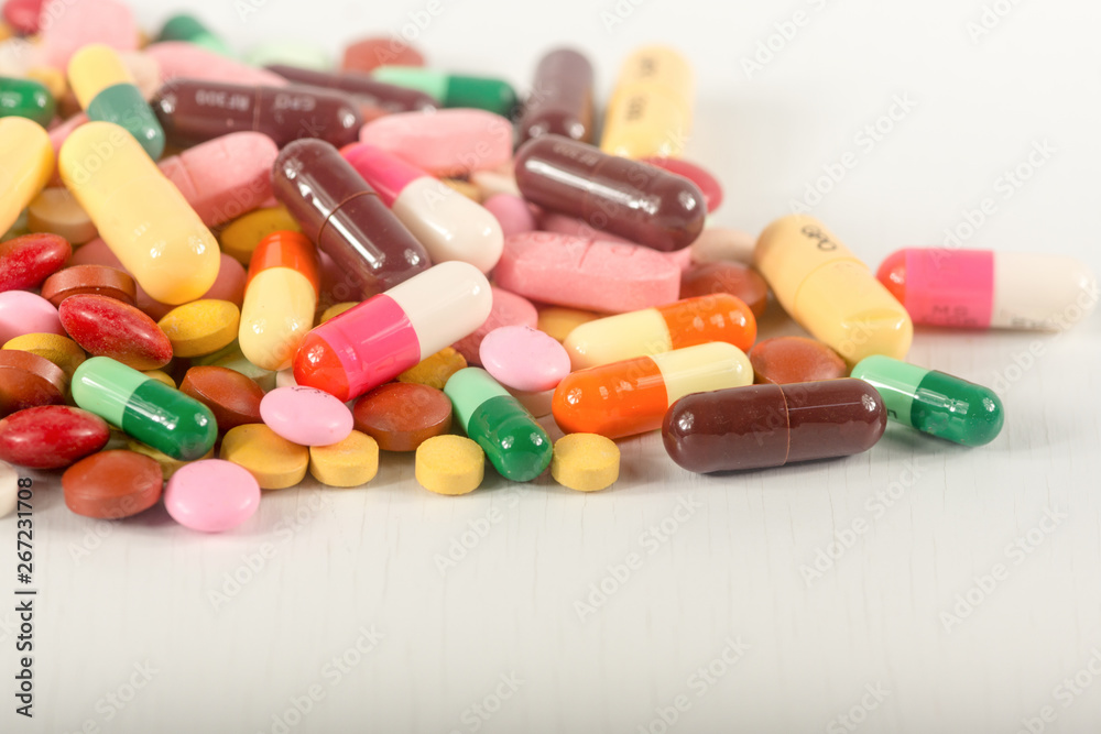 Colorful pills splatter on white background.The different tablets and capsule heap mix therapy drugs. Colorful pills splatter on white background.The different tablets and capsule heap mix therapy drugs.