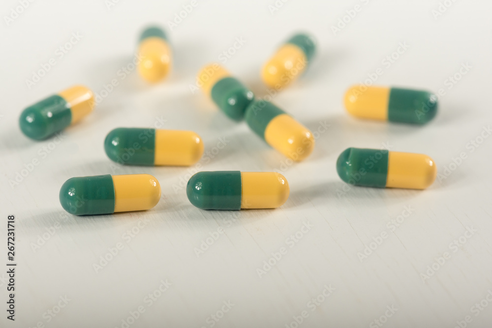 Green, yellow tramadol capsule pills on white background.Pain killer capsules called 