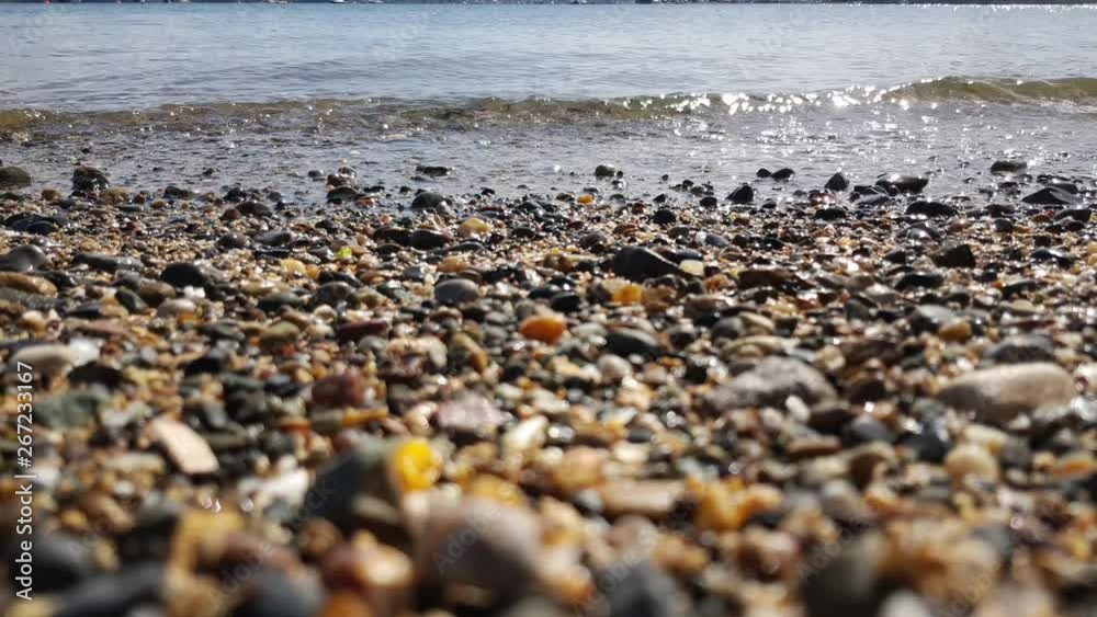 As the gentle crystal clear waves lap the shore over the pebbles and sand. As the gentle crystal clear waves lap the shore over the pebbles and sand.