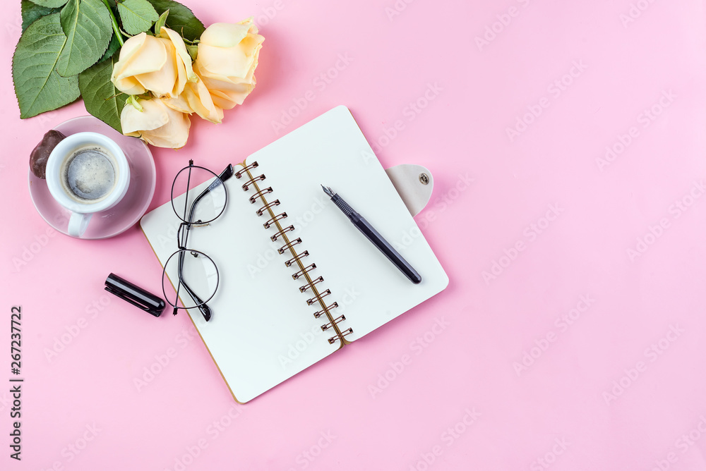 Morning coffee mug with glasses, empty notebook, pencil and rose on pink table top view . Woman working desk. Morning coffee mug with glasses, empty notebook, pencil and rose on pink table top view . Woman working desk.