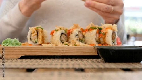 Woman eatinf sushi rolls in japanese restaurant, close up photo