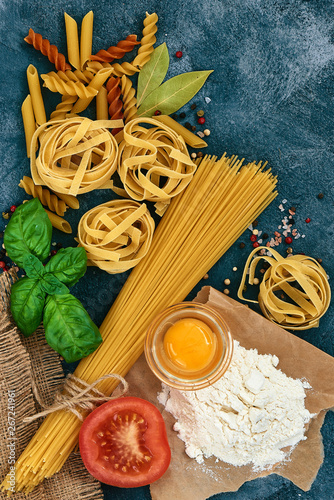 Italian pasta mix, ingredients for cooking, served on a navy grungy background. Top view photo