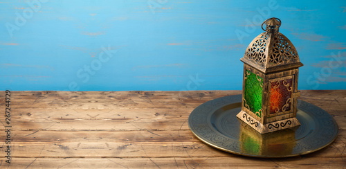 Lightened lantern on wooden table over blue background. photo